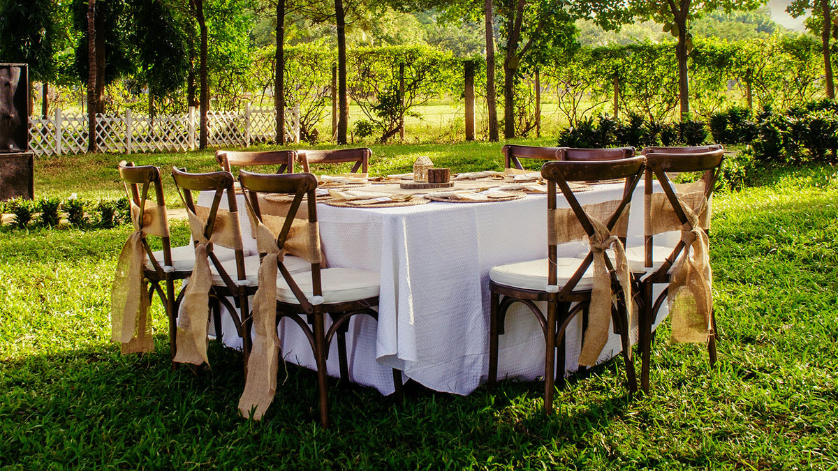 table with for a party decorated chairs on a green in a garden