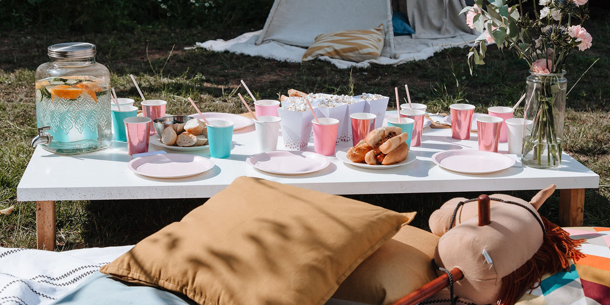 a low table in the garden with food and drinks for a party