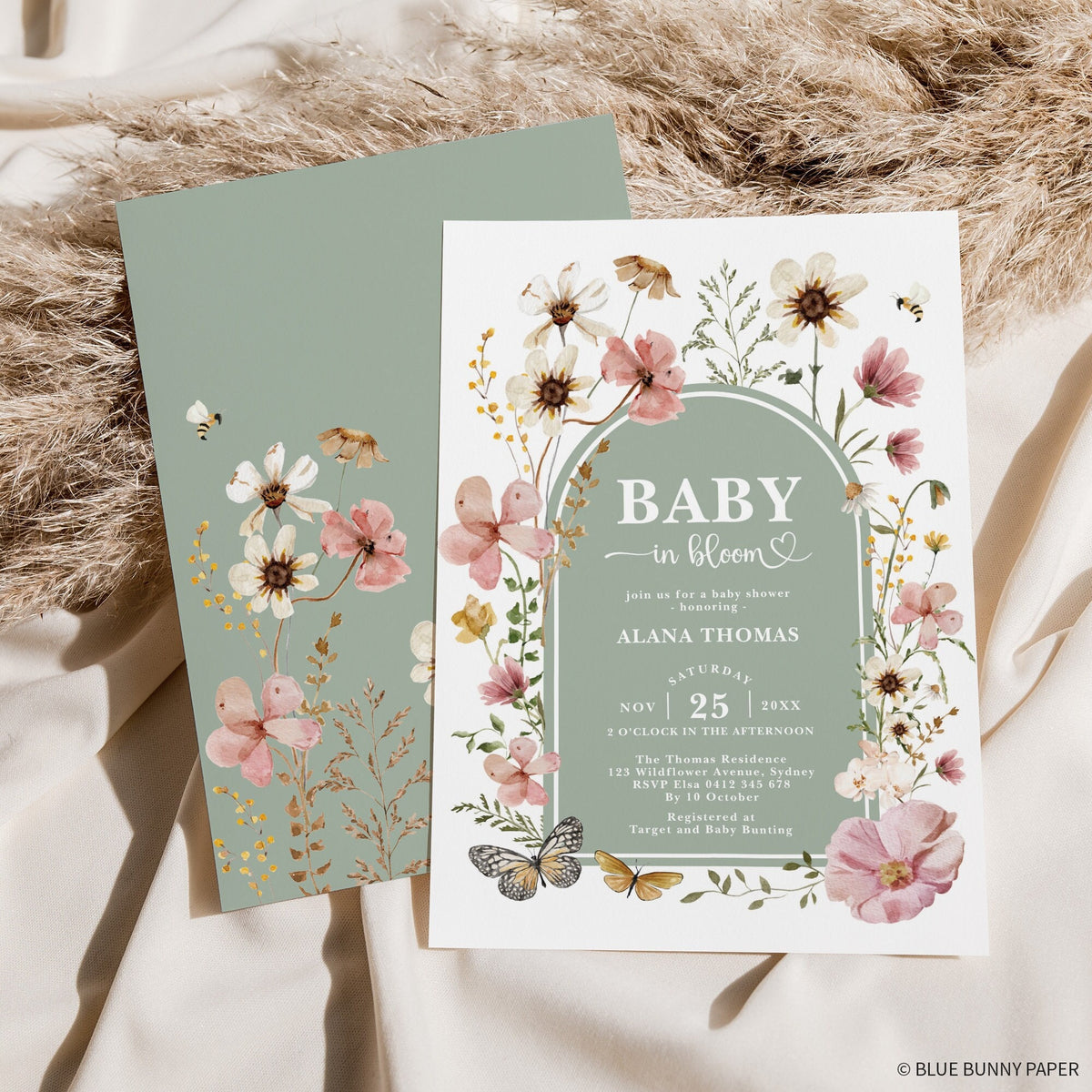 Wildflower baby in bloom invitation in front of its sage green back, on soft linen