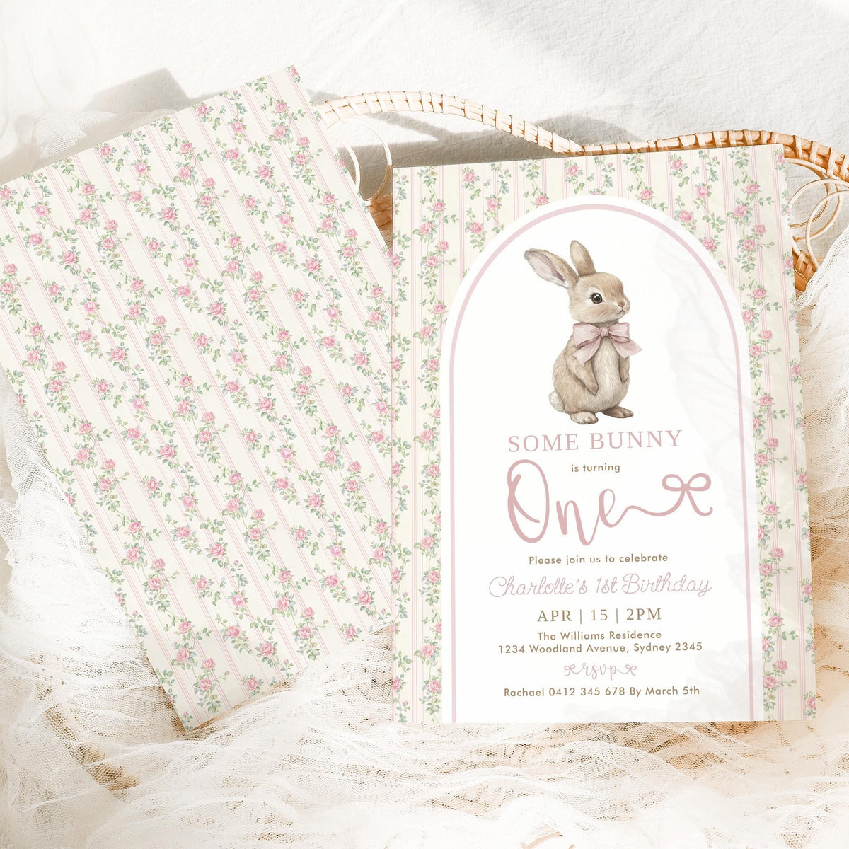 The invitation against its rose-stripe back, resting in a woven basket with white lace