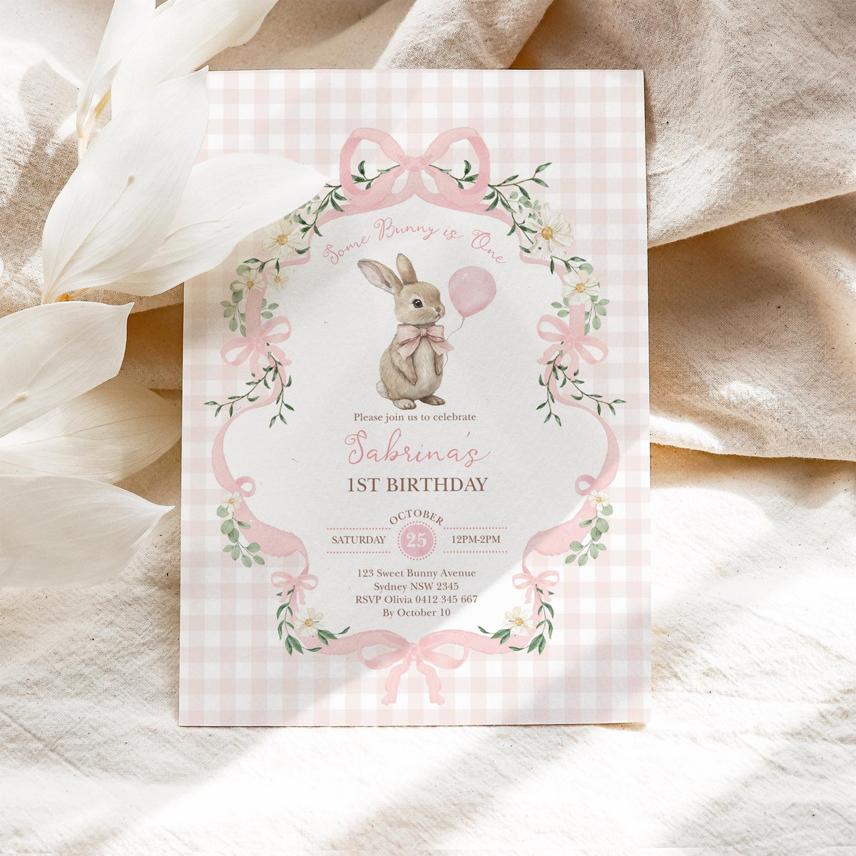 Invitation laid flat on natural linen with dried white flowers beside it