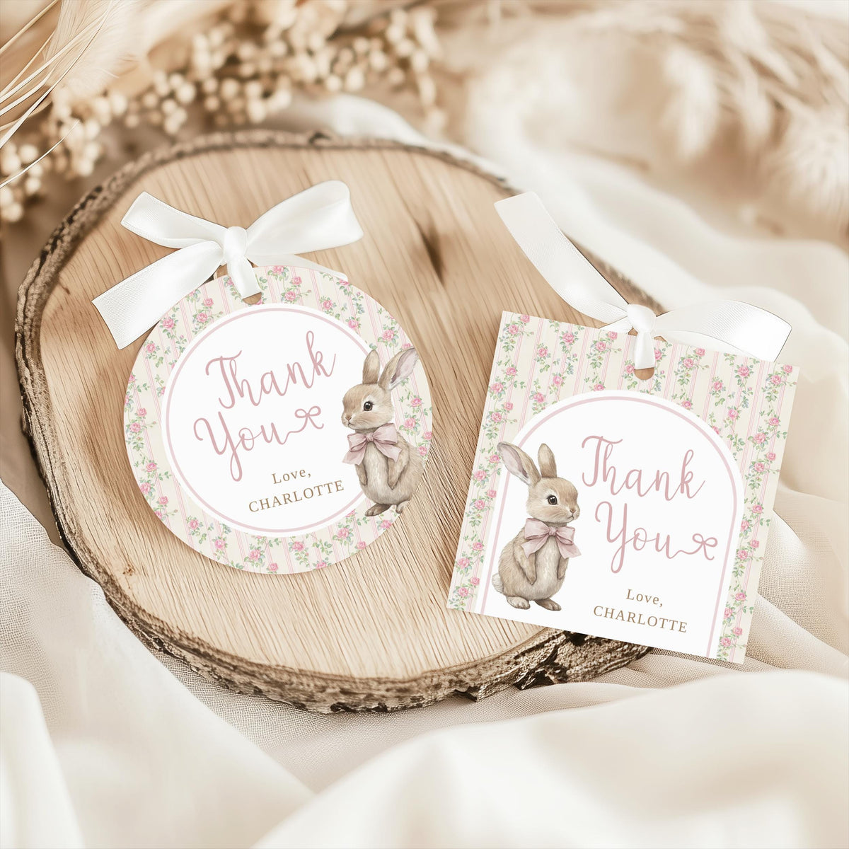 Round and square thank-you tags with white ribbon bows on a wood slice, close up