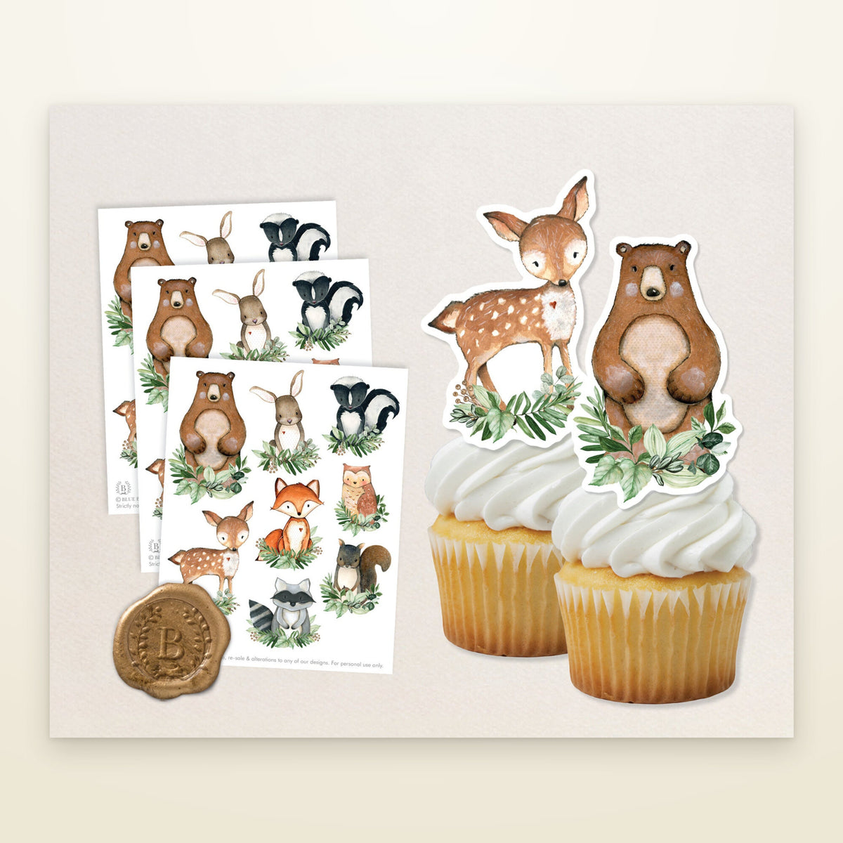 Woodland animal cake toppers cut out and standing on two frosted cupcakes beside three printed sheets