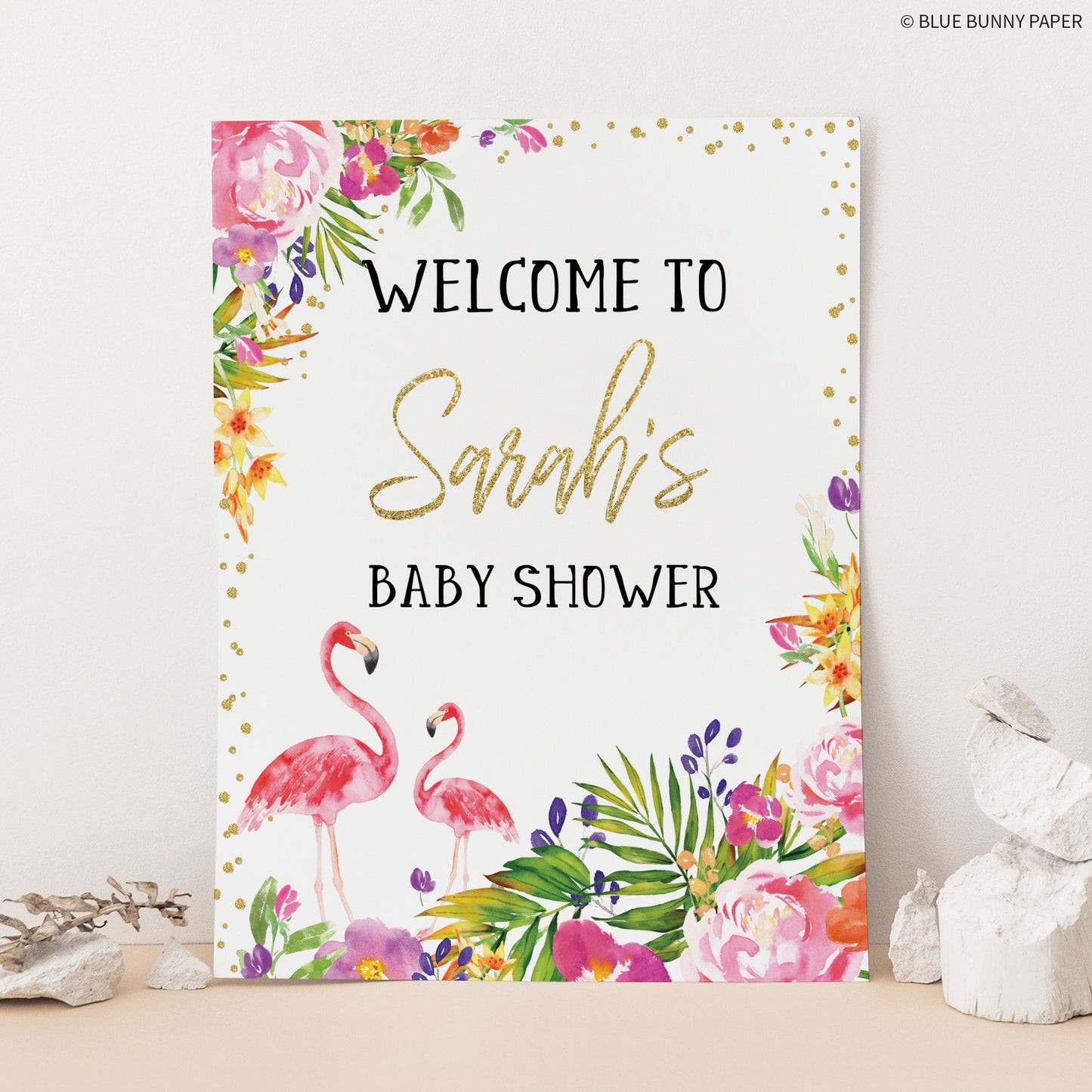 Flamingo Baby Shower Welcome Sign leaning on a wall with stones next to it