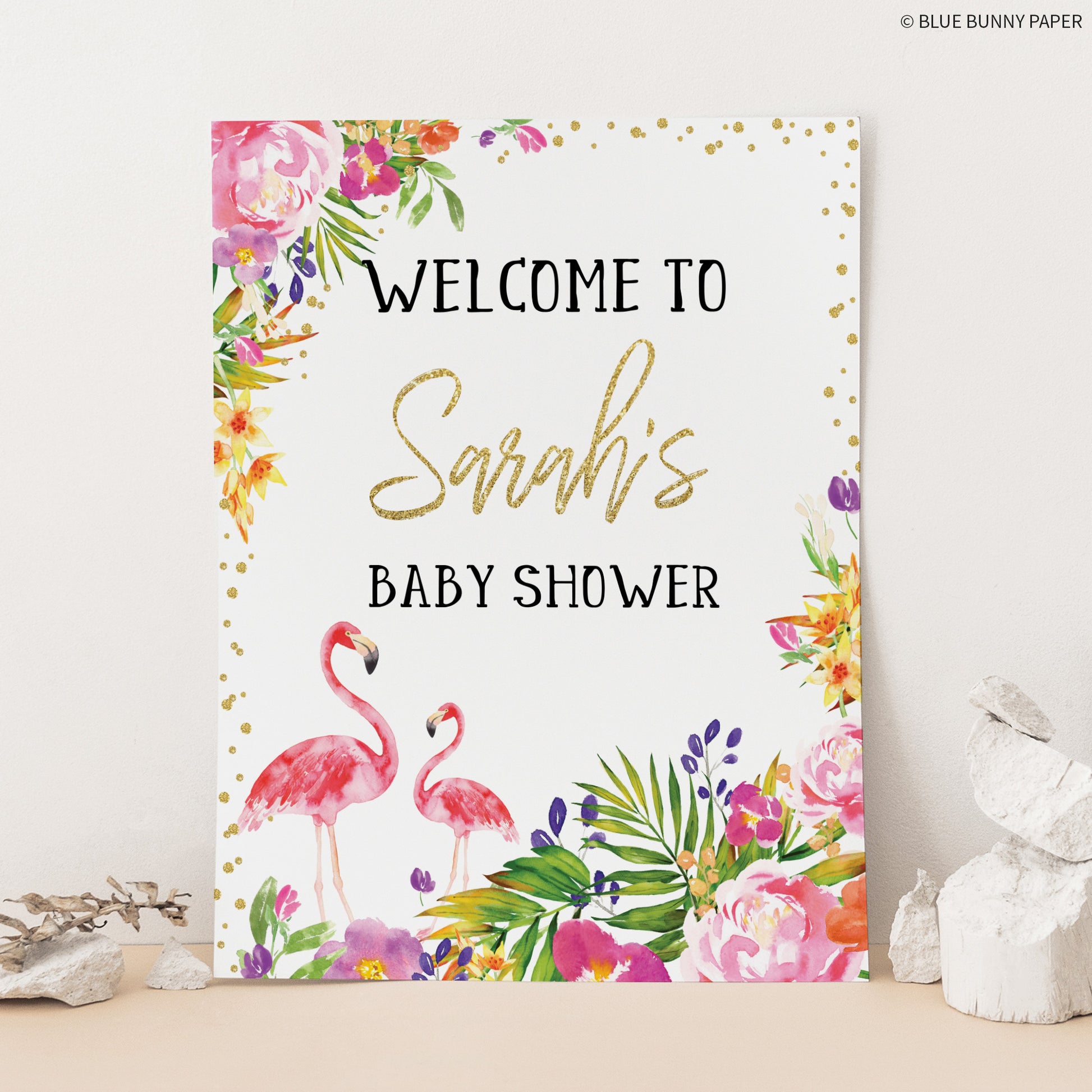 Flamingo Baby Shower Welcome Sign leaning on a wall with stones next to it